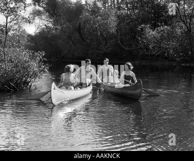 1930ER JAHRE SOMMER GRUPPE VON FÜNF JUNGEN MÄNNERN & FRAUEN IN ZWEI KANUS PADDELN EINE FLUSSABWÄRTS Stockfoto