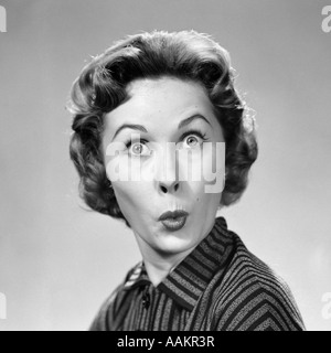 1950ER JAHREN FRAU MAKING FUNNY FACE AUGEN BREITERE LIPPEN GESCHÜRZT WIE EIN KUSS ODER EINE PFEIFE, BLICK IN DIE KAMERA Stockfoto