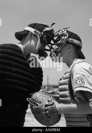 1950ER JAHRE JUNGEN IN BASEBALL UNIFORMEN VON ANGESICHT ZU ANGESICHT STREITEN SCHIEDSRICHTER & CATCHER Stockfoto