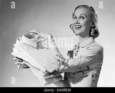 1950ER JAHREN STOLZ LÄCHELND FRAU HAUSFRAU HÄLT FRISCH GEWASCHENEN HEMDEN Stockfoto