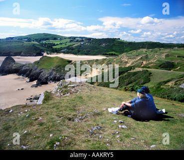 Ehepaar sitzt auf einer Bank auf Pennard Cliffs und blickt auf die Three Cliffs Bay, Gower Peninsula, South Wales. Stockfoto