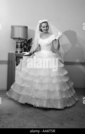 1950S 1960S BRAUT IM VOLLEN KLEID SCHLEIER & WEIßE HANDSCHUHE IN RAUM MIT OFFENER TÜR Stockfoto