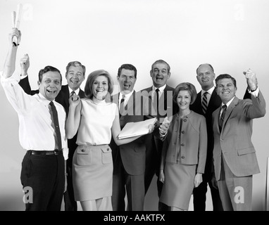 1970ER JAHRE WHITE COLLAR BÜROANGESTELLTEN MÄNNER UND FRAUEN JUBELN, BLICK IN DIE KAMERA Stockfoto