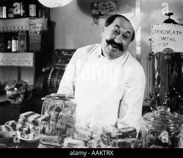 1930ER JAHRE VINTAGE PORTRÄT DES LÄCHELNDEN INHABERS TRESEN IM KAFFEE UND SÜßEN SHOP BLICK IN DIE KAMERA Stockfoto