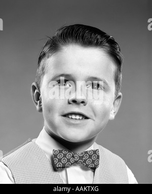 1950ER JAHRE LÄCHELNDEN PORTRAIT JUNGER MANN JUNGE TRÄGT KARIERTE WESTE UND POLKA DOT BOW-TIE Stockfoto