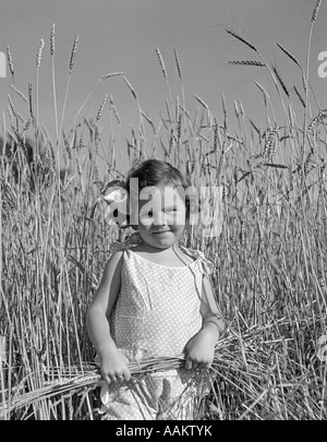 1930ER JAHRE NIEDLICHE KLEINE MÄDCHEN STEHEN WEIZENFELD Stockfoto