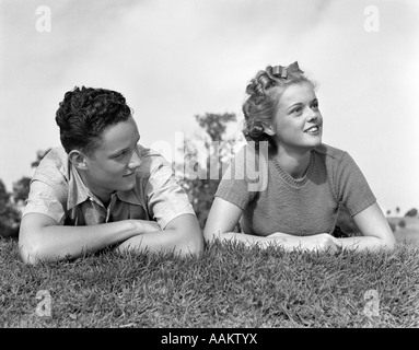 1930S 1940S JUNGES TEEN PAAR LIEGEN IM GRASS KOPFPORTRÄT SCHULTERN Stockfoto