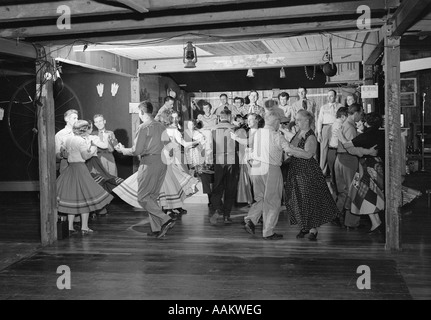 1950ER JAHREN QUADRATISCHE TÄNZER IM LAND WESTLICHEN OUTFITS TANZEN ZUR MUSIK VON EINER KLEINEN GRUPPE IN EINER SCHEUNE Stockfoto