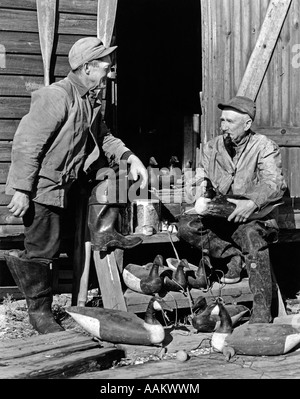 1930S 1940S KÖDER ZWEI ÄLTERE MÄNNER TRAGEN JAGDBEKLEIDUNG REPARIEREN HÖLZERNE KANADAGANS BARNEGAT BUCHT NEW JERSEY USA Stockfoto