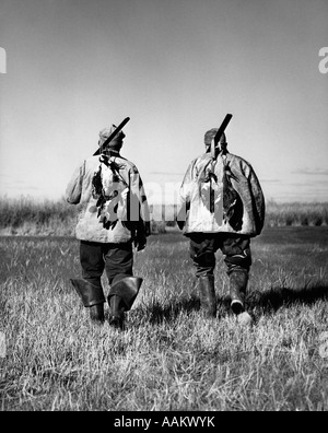 1930ER JAHREN 940S ZWEI MÄNNER ERFOLGREICHE JÄGER ZU FUß ENTFERNT MIT TOTE ENTEN UND SCHROTFLINTEN ÜBER SCHULTERN BARNEGAT BAY NEW JERSEY USA Stockfoto