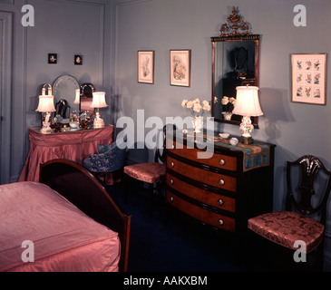 1930S 1940S SCHLAFZIMMER MIT BLAUEN WÄNDEN ROSA TAGESDECKE UND GESCHÜRZTEN EITELKEIT TABELLE Stockfoto