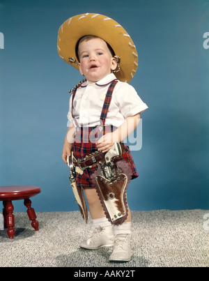 1950S 1960S KLEINER JUNGE MIT COWBOY-HUT UND ZWEI SECHS GUN CAP PISTOLEN HOLSTER STEHEND MIT HALTUNG Stockfoto