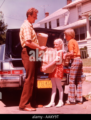 1970ER JAHREN VATER UND KINDER ENTLADEN LEBENSMITTEL AUS AUTO Stockfoto