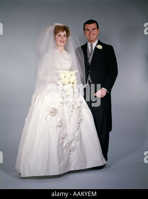1960ER JAHREN FORMALE VOLLER LÄNGE STUDIOPORTRAIT VON BRAUT UND BRÄUTIGAM Stockfoto