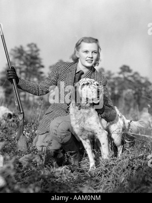 1940ER JAHREN FRAU JÄGER TRAGEN ANZUG VON TWEED SCHROTFLINTE IN EINER HAND ENGLISCH SETTER HUND MIT ANDEREN KNIEND GRAS HÄLT Stockfoto