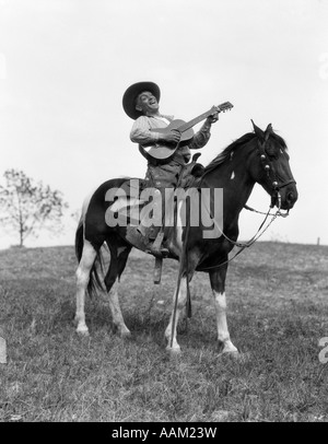 1920ER JAHRE COWBOY AUF PFERD SINGEN & SPIELT GITARRE Stockfoto
