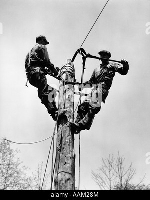 1930S 1940S DRAHT ZWEI MÄNNER ARBEITEN AN ELEKTRISCHEN POLE SCHNEIDEN Stockfoto