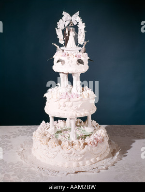 DREISTUFIGE HOCHZEITSTORTE MIT ROSA UND WEIßEM ZUCKERGUSS HOCHZEITSPAAR ON TOP Stockfoto