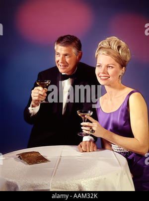 1960S 1970S PAAR MANN UND FRAU IN FORMALEN SMOKING UND ABENDKLEID LÄCHELND TOASTEN MIT CHAMPAGNER-GLÄSER Stockfoto