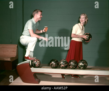 1950ER JAHREN LÄCHELND PAAR IN DER KEGELBAHN FRAU MIT BALL MANN MIT GLAS BIER, DEN ICH Stockfoto