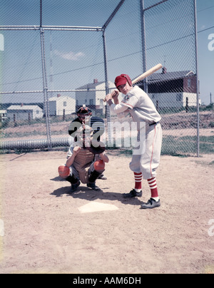 1950ER JAHREN 3 KINDER SPIELEN LITTLE LEAGUE BASEBALL BAT HOME PLATE TEIG CATCHER SCHIEDSRICHTER SAND VIEL ZAUN UNIFORMEN SPORT Stockfoto