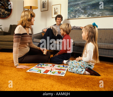 1970 1970S FAMILIE MUTTER VATER JUNGE MÄDCHEN SPIELEN SPIEL WOHNZIMMER TEPPICH RETRO-PARCHESSI FAMILIEN AKTIVITÄT BRETTSPIELE Stockfoto