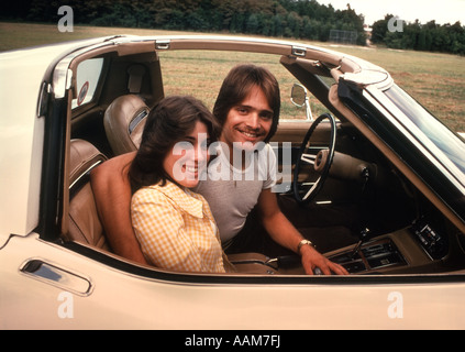 1970 1970S GLÜCKLICH LÄCHELNDE PAAR JUNGE MANN FRAU SITZEN COCKPIT CORVETTE AUTO SPORTWAGEN Stockfoto