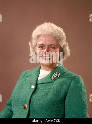 1960 1960S LÄCHELND REIFE SENIOR ÄLTERE FRAU SILBERNES HAAR GRÜNE WOLLE JACKE PIN BROSCHE FRAUEN SENIOREN PORTRAIT Stockfoto