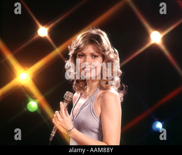 1970 1970S SÄNGERIN SÄNGER HALTEN LICHTER HINTERGRUND MIKROFON BÜHNE SINGEN SÄNGER SINGEN PERFORMER FRAU FRAUEN Stockfoto