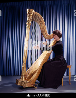 1950ER 1960ER JAHRE 1970ER JAHREN RETRO-FRAU MUSIKER SPIELEN GROßE KLASSISCHE HARFE INSTRUMENT Stockfoto