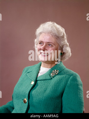 1960ER JAHRE PORTRAIT LÄCHELND GRAUEN HAAREN SENIORIN IN GRÜNE WOLLE STRICKEN ANZUG BROSCHE AM REVERS SENIOR REIFEN Stockfoto