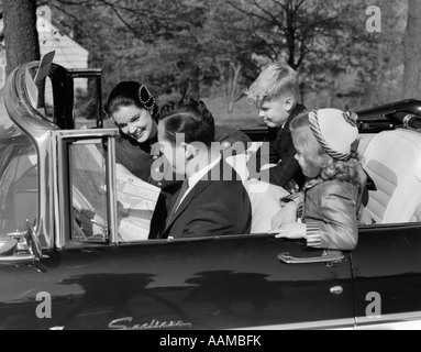 1950ER JAHRE FAMILIE VATER MUTTER TOCHTER SOHN IM CABRIO READING KARTE Stockfoto