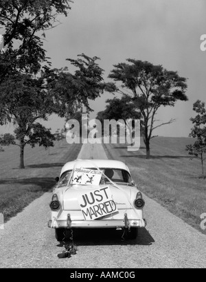 RÜCKSEITE DES WEIßEN FORD SEDAN ANFAHREN MIT JUST MARRIED ZEICHEN DER 1950ER JAHRE AUF STAMM Stockfoto