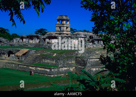 Blick durch die Bäume von zwei Touristen zu Fuß an der Unterseite des Steins Maya Tempel namens The Palace in Palenque, Mexiko Stockfoto