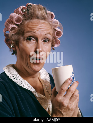PORTRÄT DER FRAU TRAGEN LOCKENWICKLER UND ROBE HOLDING TASSE KAFFEE FOOD BEVERAGE SYMBOLISCHE Stockfoto