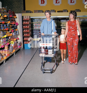 1970 1970S ZWEI FRAUEN KLEINE MÄDCHEN GEHEN DOWN SUPERMARKT LEBENSMITTELGESCHÄFT GANG FRAU DRÄNGEN CART KART LEBENSMITTEL LÄDEN Stockfoto