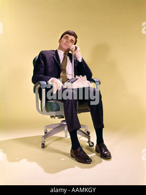 1960S 1970S BUSINESS-MANN IM BÜRO STUHL DREHBAR AM TELEFON SPRECHEN Stockfoto