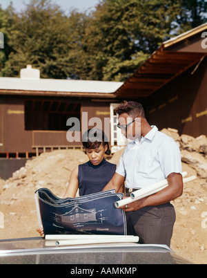 1960ER JAHREN AFROAMERIKANISCHEN PAAR BLICK AUF BLAUPAUSE PLÄNE FÜR NEUES HAUS IM BAU Stockfoto