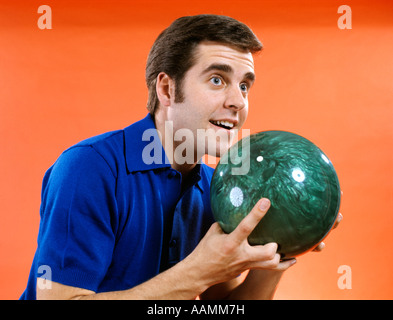1960ER JAHREN NAHAUFNAHME DER JUNGE MANN, DER BOWLINGKUGEL BOWL BEREIT HÄLT Stockfoto