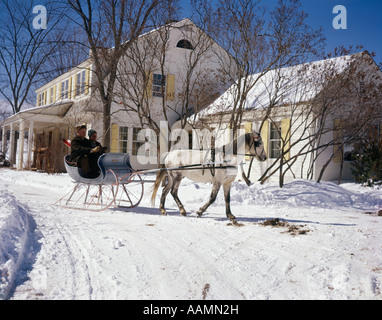 1960ER JAHRE SCHNEE 2 MÄNNER IN EIN WEIßES PFERD GEZEICHNETEN OFFENEN SCHLITTEN VON HAUS LANDGASTHOF RETRO VINTAGE WINTER VERMONT Stockfoto