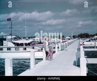 1950ER JAHREN 2 JUNGE FRAUEN IN SHORTS SANDALEN AUF LANGE MARINA PIER ANGELN VERGNÜGEN BOOTE BAHIA MAR FT. LAUDERDALE FL Stockfoto