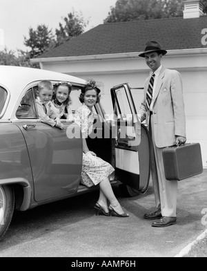 1950ER JAHRE MANN VATER HOLDING KOFFER UND ERÖFFNUNG AUTO TÜR FÜR FRAU MUTTER TOCHTER UND SOHN IM HINTEREN SITZ Stockfoto