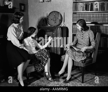 1940ER JAHREN DREI JUNGE MÄDCHEN SITZEN IM WOHNZIMMER RADIO HÖREN Stockfoto