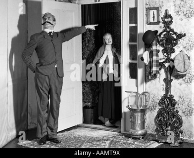 1960ER JAHRE AUFBAU DES VIKTORIANISCHEN MANN MIT SCHNURRBART VERBANNEN FRAU IN TÜR Stockfoto