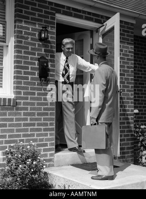 1950ER JAHRE VERKÄUFER GESPRÄCH MIT MANN AN HAUSTÜR Stockfoto