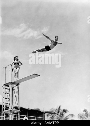 1930S 1940S FORMSCHÖNE FRAU BEOBACHTETE MAN KOPFSPRUNG HOHEN SPRUNGBRETT Stockfoto