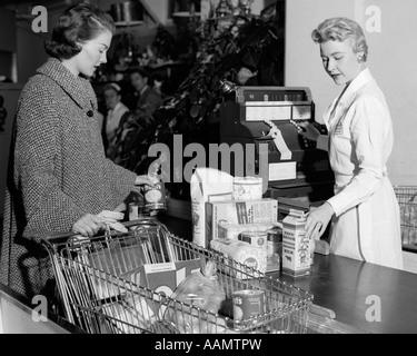 1950ER JAHREN FRAU AN DER SUPERMARKT KASSE ZÄHLER ÜBERGABE ARTIKEL ÜBER FÜR KASSIERER, RING OBEN AUF KASSE Stockfoto