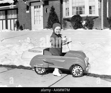 1930S 1940S KLEINER JUNGE SPIELT IM SPIELZEUGAUTO AUßERHALB IN SCHNEE Stockfoto