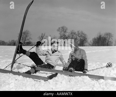 1930ER JAHREN PAAR MANN UND FRAU AUF SKIERN IM SCHNEE LACHEN FALLEN Stockfoto