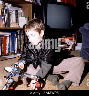 Ein kleines britisches Kind zu Hause, das auf dem Boden im Wohnzimmer sitzt und mit einem Transformatorenspielzeug in Cardiff Wales UK KATHY DEWITT spielt Stockfoto